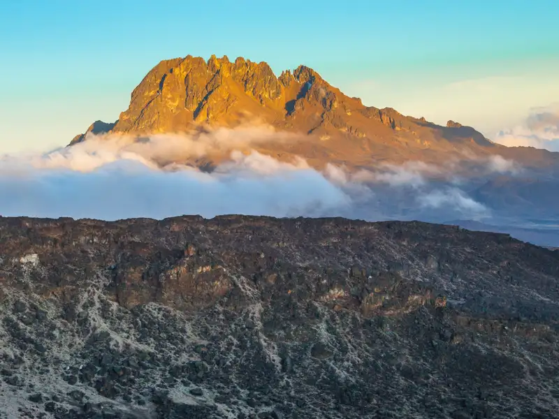 Goldener Berggipfel in der Abendsonne mit Wolkenformationen.