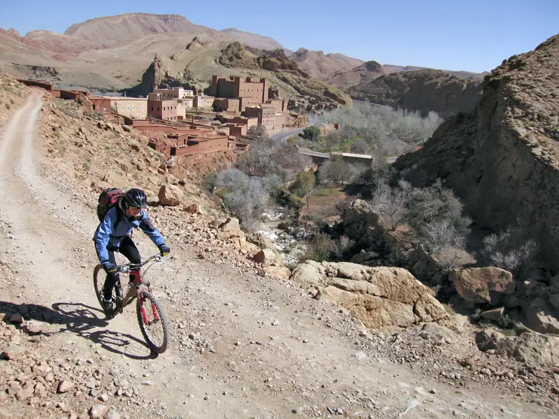 Mountainbiker auf einem Bergpfad in der Nähe einer traditionellen Siedlung.