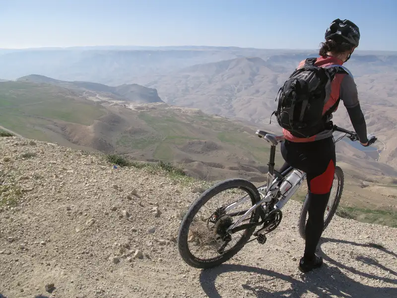 Mountainbiker auf einem Bergpfad mit Blick auf eine weite Landschaft.