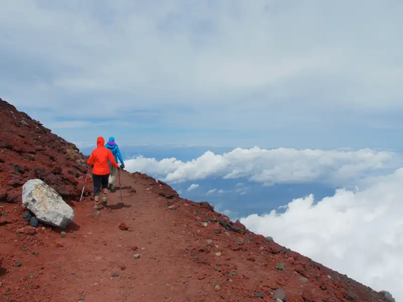 Wanderer auf einem Bergpfad über den Wolken.