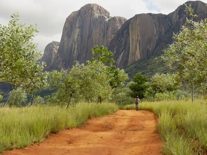 Radfahrer auf einem Feldweg vor beeindruckenden Felsformationen.