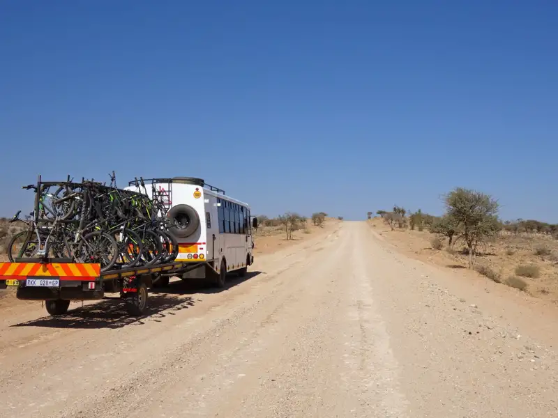 Bus mit Fahrradanhänger auf einer unbefestigten Straße.
