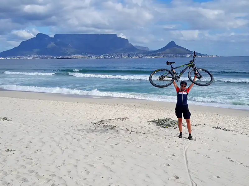 Radfahrer am Strand mit dem Tafelberg im Hintergrund.