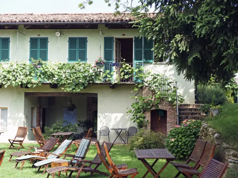 Gartenbereich mit Liegestühlen und Sitzgelegenheiten. Das Gebäude der Unterkunft im Hintergrund.