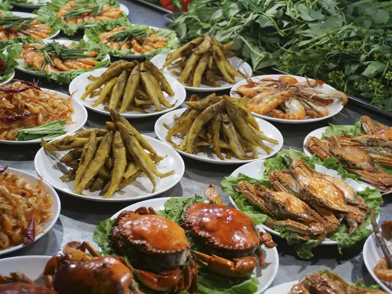 Teller mit verschiedenen Meeresfrüchten wie gebratenen Fischen, Garnelen und Krabben.