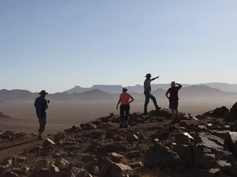 Wandergruppe auf einem Aussichtspunkt mit Blick auf die Wüste.