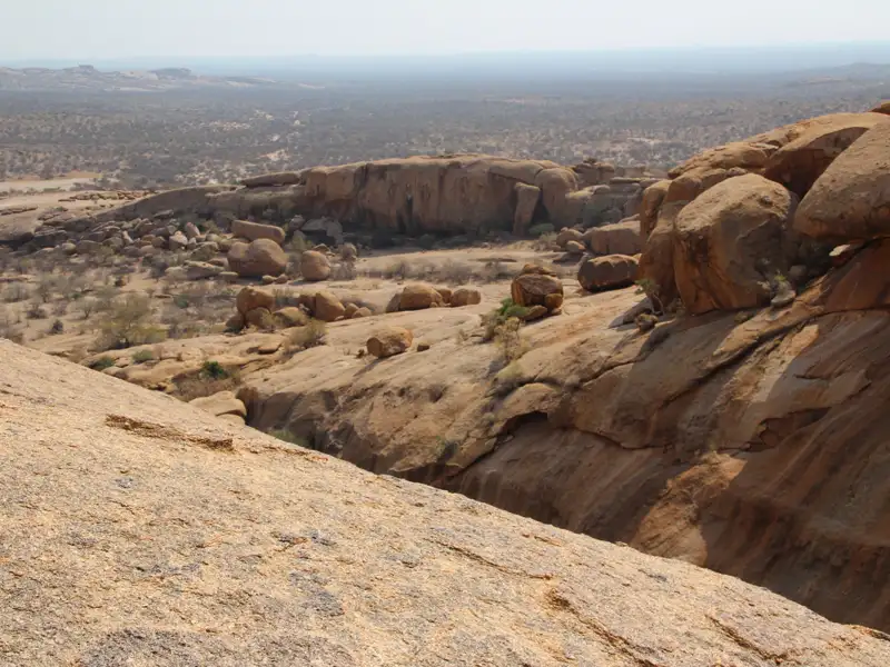 Felsige Landschaft mit verstreuten Büschen und Felsformationen.