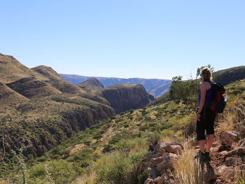 Wanderer auf einem Bergpfad mit Blick auf eine tiefe Schlucht.