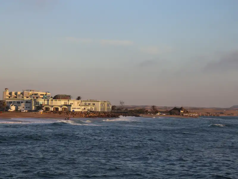 Küstenlandschaft mit Gebäuden und Wellen.