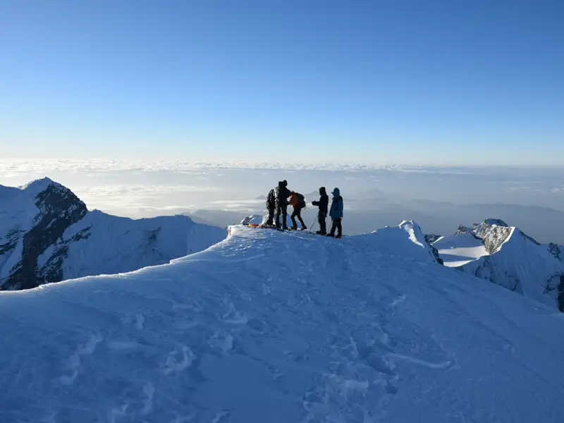 Bergsteiger auf einem verschneiten Berggipfel.