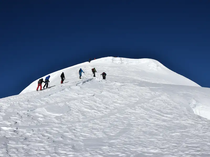 Bergsteigergruppe beim Aufstieg eines verschneiten Berges.