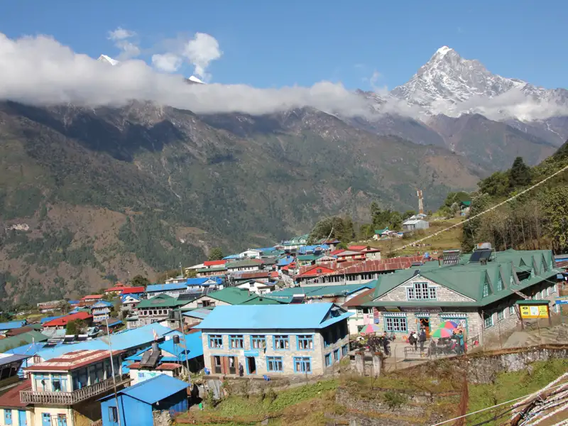Bergdorf im Himalaya mit Blick auf einen schneebedeckten Gipfel.