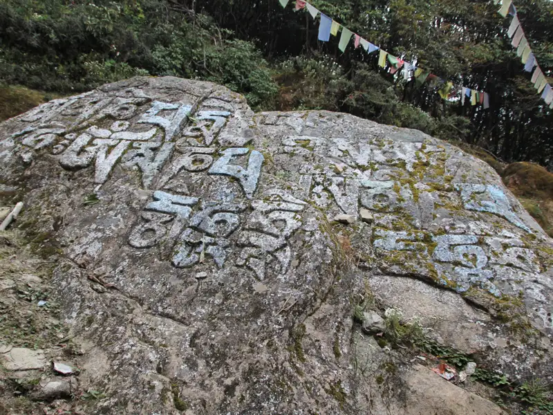 Religiöse Inschriften auf einem Felsbrocken, möglicherweise Mantras, die von Wanderern auf ihrer Reise hinterlassen wurden.