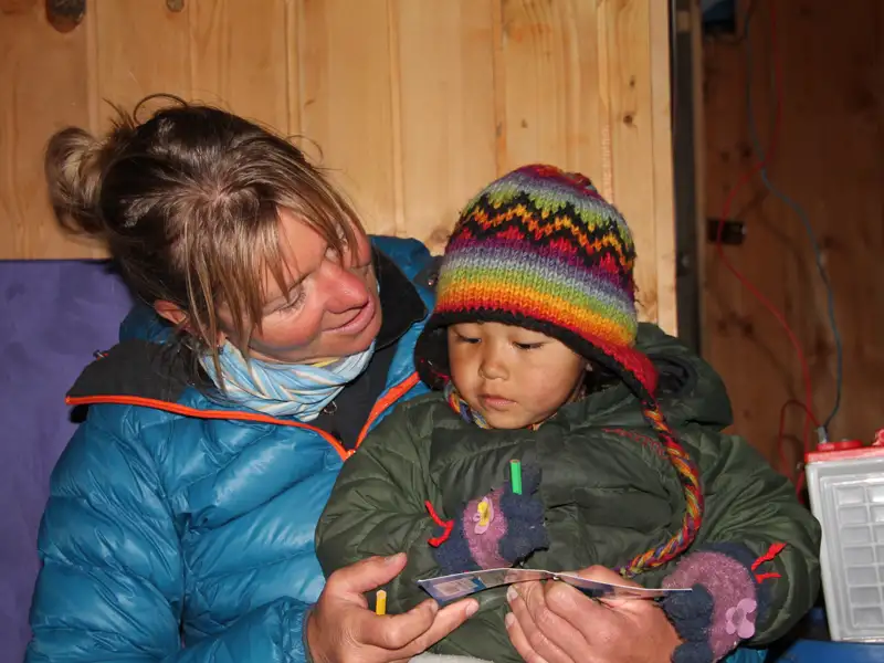 Reisende liest einem Kind in einer Hütte etwas vor.