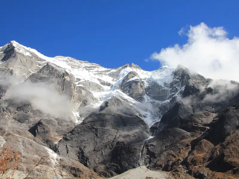 Schneebedeckte Berge mit Wolkenformationen und felsigen Hängen.