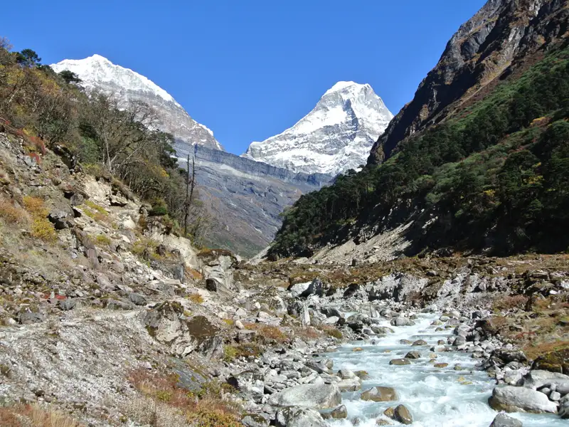 Gebirgsbach und schneebedeckte Gipfel im Himalaya.