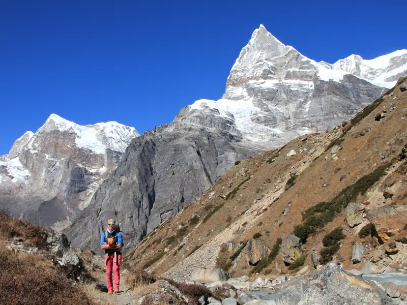 Wanderer auf einem Himalaya-Pfad mit Blick auf schneebedeckte Gipfel.