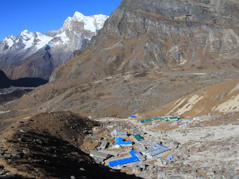 Gebäude mit blauen und grünen Dächern in einer Berglandschaft.
