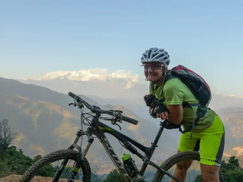 Mountainbikerin macht Pause auf einem Bergpfad mit Blick auf die Berge.