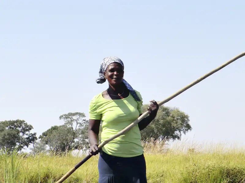Frau stakt mit langem Stock im Fluss.