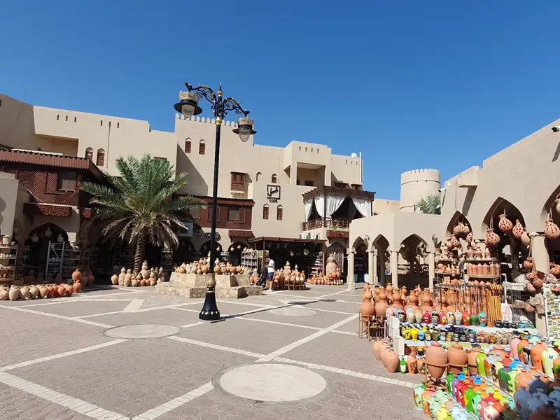 Marktstände mit Keramikwaren vor traditioneller Architektur.