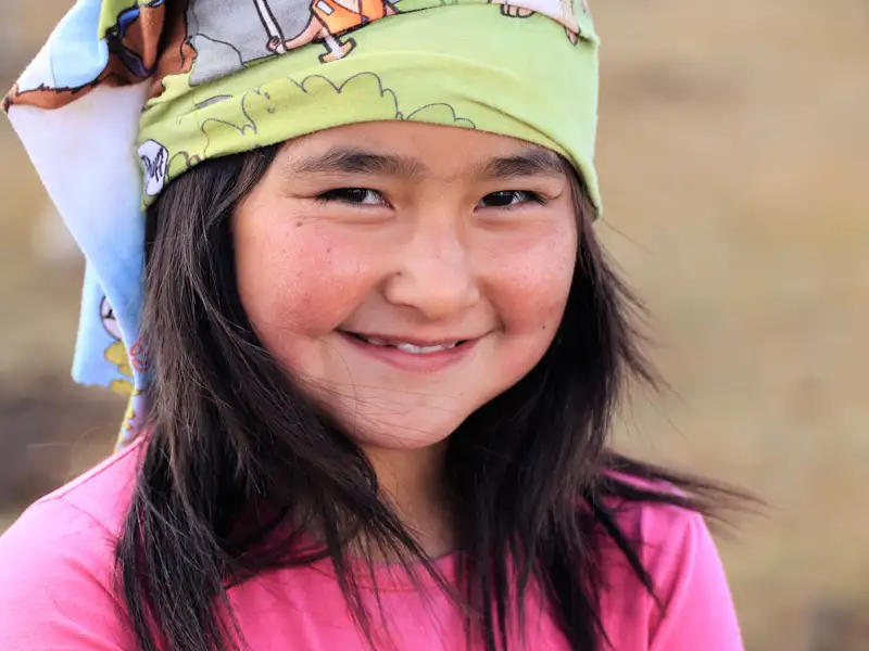 Lächelndes Mädchen mit buntem Kopftuch.