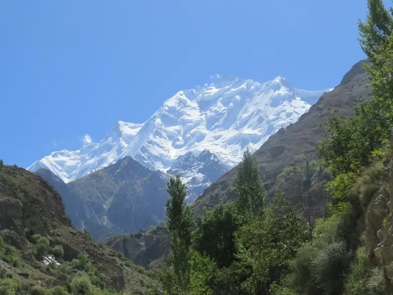 Panorama eines schneebedeckten Berges, der über einem grünen Tal aufragt.