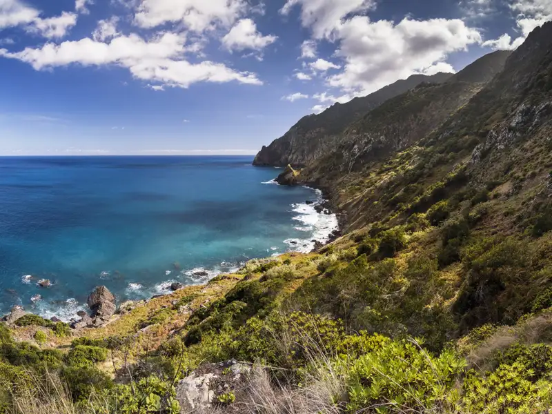 Felsige Küste mit Blick auf das blaue Meer unter einem bewölkten Himmel.