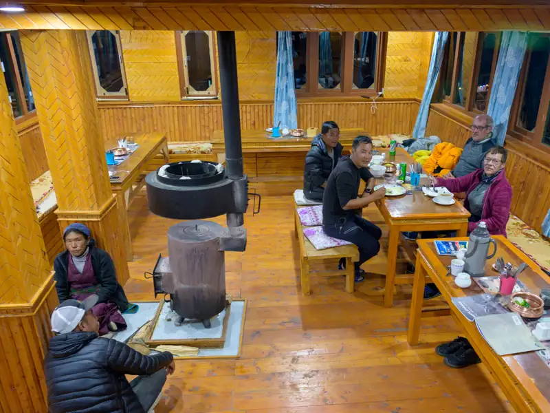Reisende wärmen sich beim Abendessen in einer Hütte mit Holzofen auf.