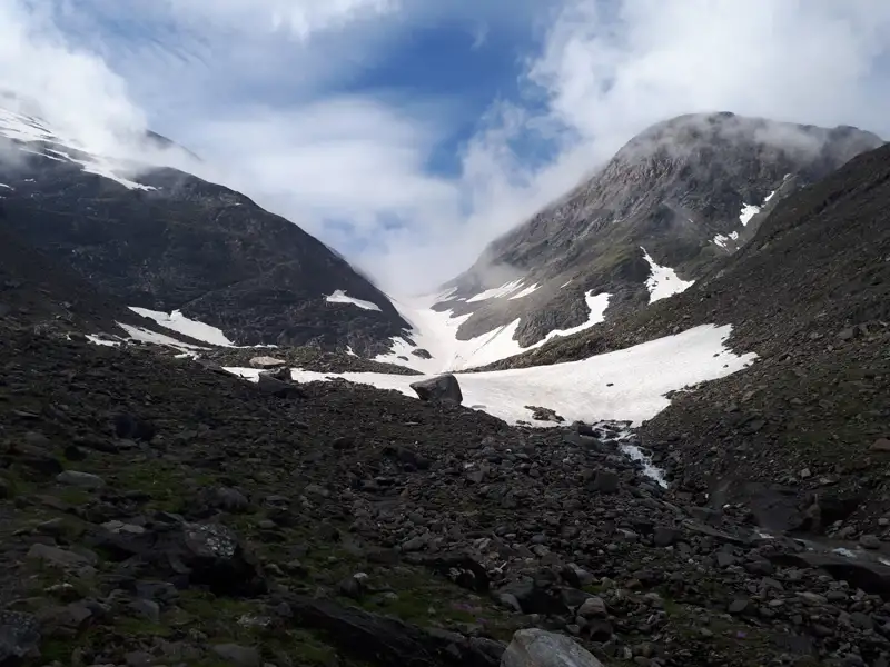 Schnee und Geröll in einem Gebirgstal.