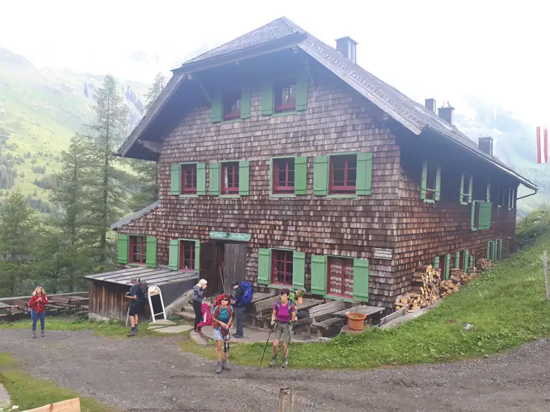 Wanderer ruhen sich vor einer Berghütte aus.
