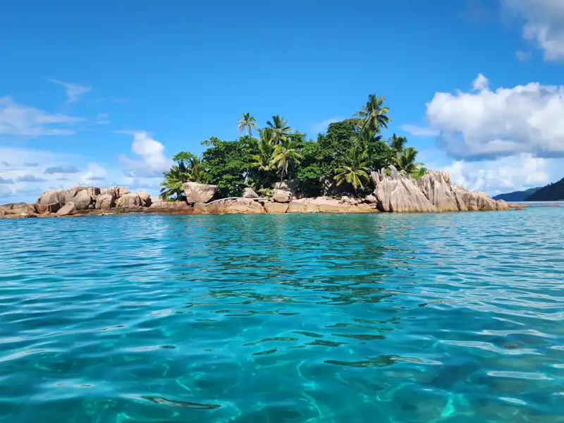 Kleine Insel mit Palmen und türkisfarbenem Wasser.
