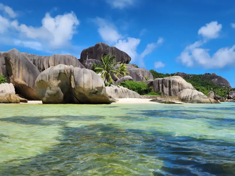Granitfelsen und türkisfarbenes Wasser an einem tropischen Strand.