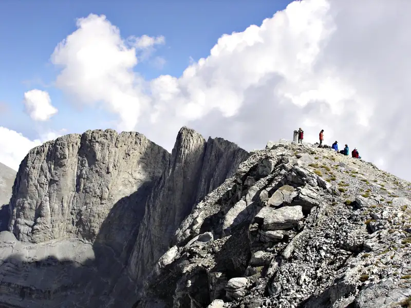 Wanderer auf einem Berggipfel mit Blick auf die umliegenden Berge.