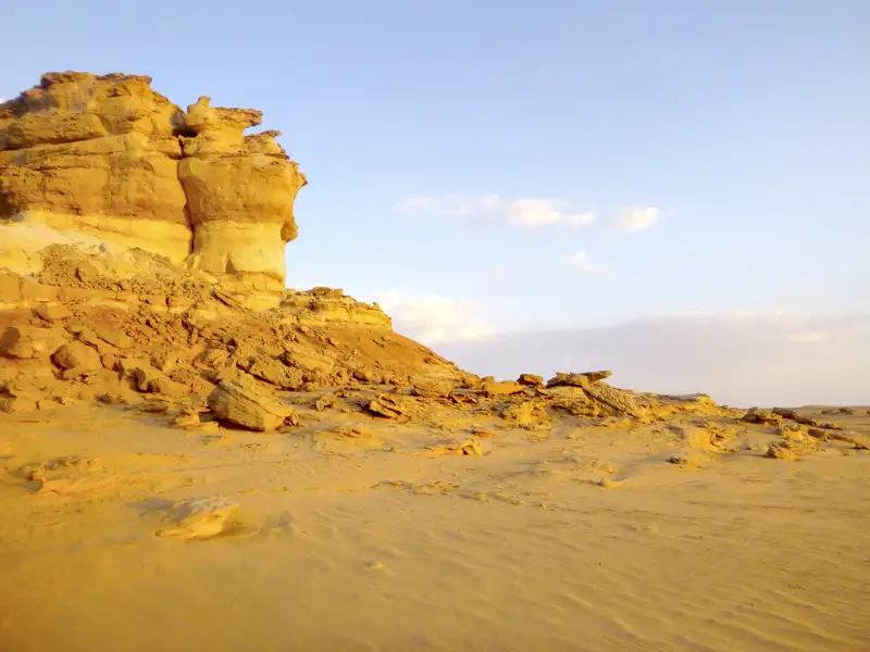 Eine markante Felsformation in einer sandigen Wüstenlandschaft.