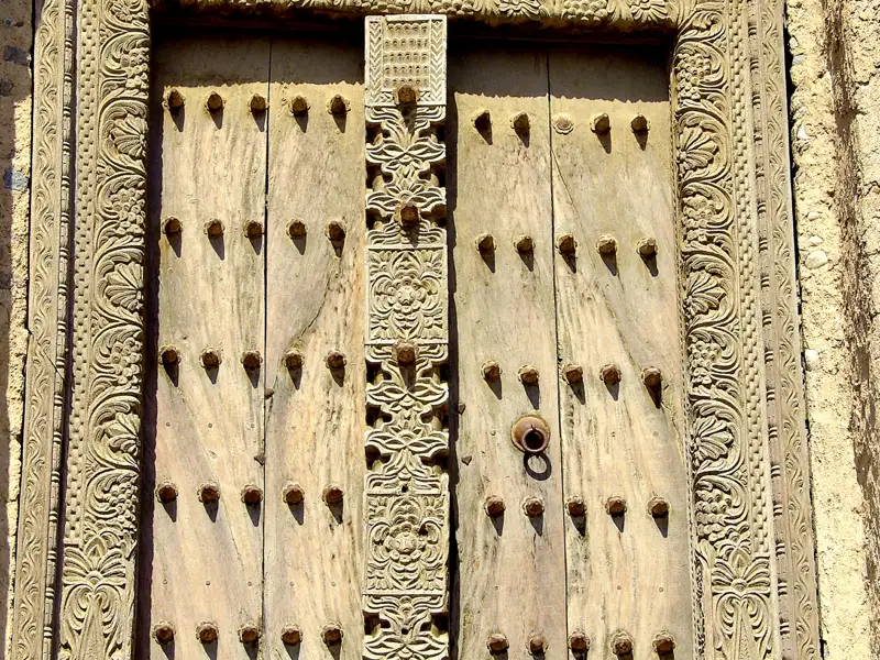Nahaufnahme einer traditionellen Holztür mit aufwendigen Schnitzereien und Metallbeschlägen.