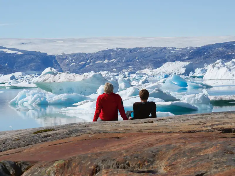Campingplatz mit Zelten und Eisbergen im Hintergrund.