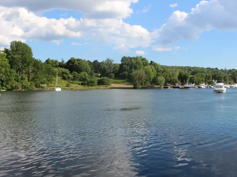 See mit Booten und bewaldetem Ufer.