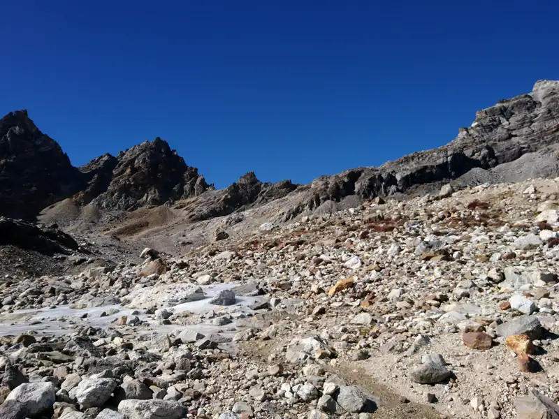 Steinige Berglandschaft mit Bach und Gipfeln.