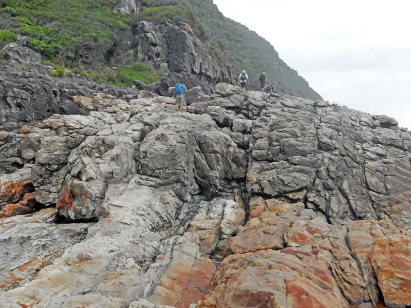 Wanderer auf felsiger Küstenlandschaft.