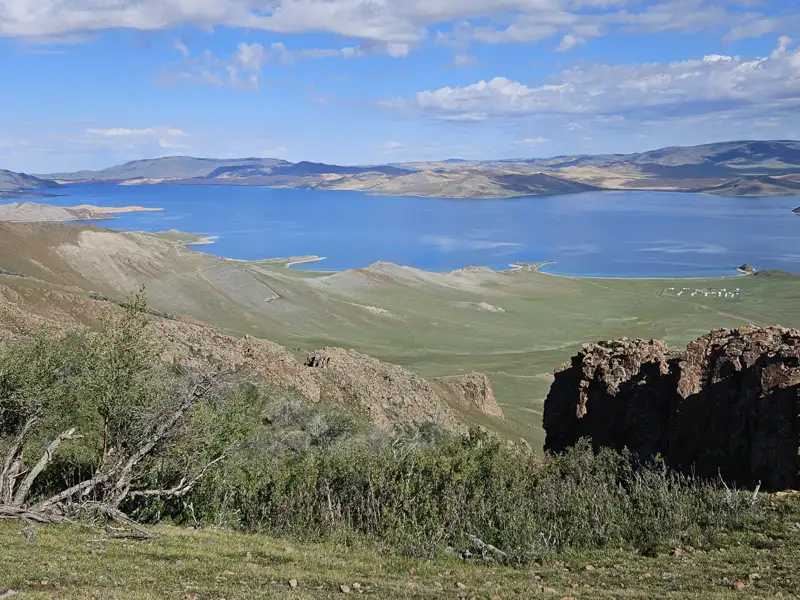 Panoramablick auf einen See mit Hügeln und Vegetation.