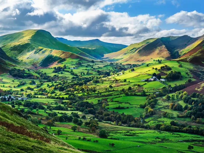 Landschaftsbild eines grünen Tals, umgeben von Bergen.