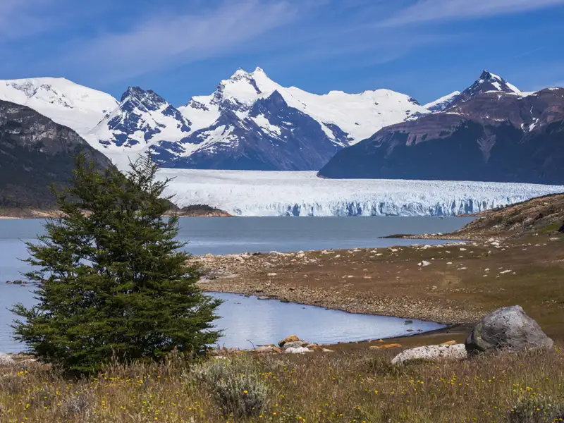 Panoramablick auf einen Gletscher, der in einen See kalbt, mit imposanten Bergen im Hintergrund.