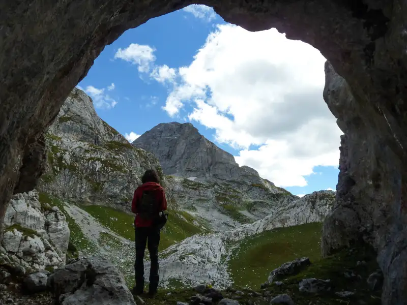Wanderer in einer Höhle mit Blick auf die Berge.