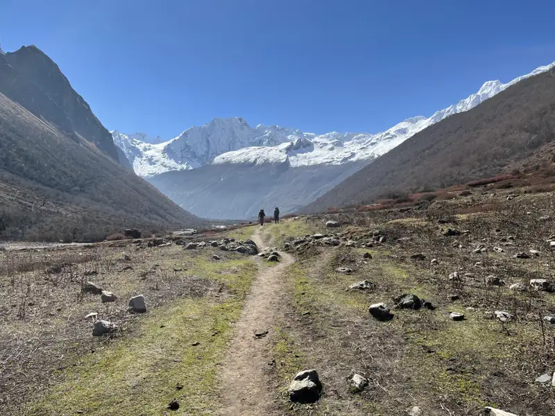 Wanderer auf einem Bergpfad im Himalaya mit Blick auf die schneebedeckten Gipfel.