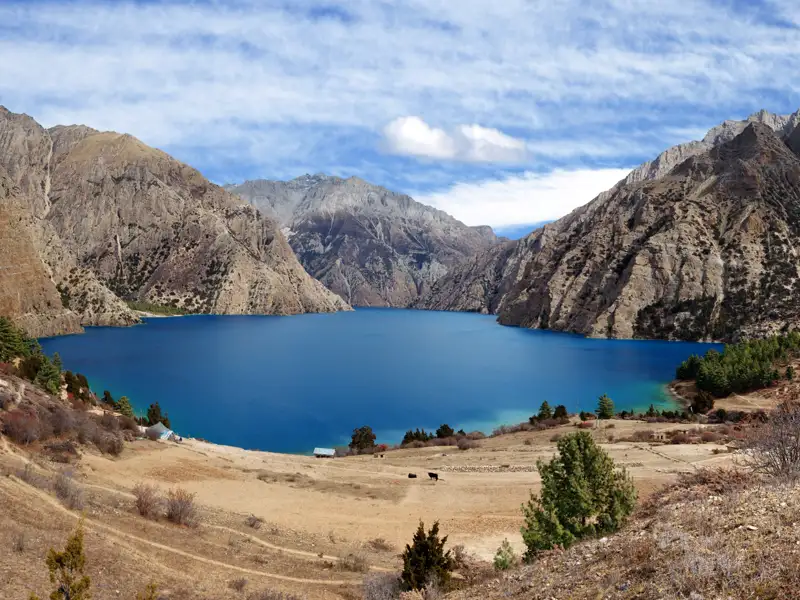 Panoramablick auf einen tiefblauen Bergsee, umgeben von einer kargen Landschaft und steilen Berghängen.