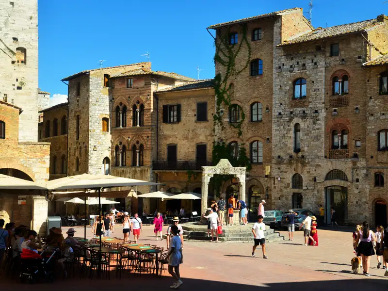 Mittelalterliche Piazza in San Gimignano mit umliegenden Gebäuden und Touristen.