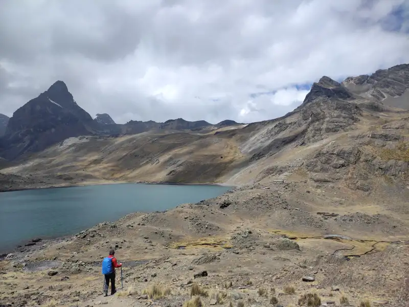 Wanderer am Ufer eines Bergsees inmitten einer Gebirgslandschaft.