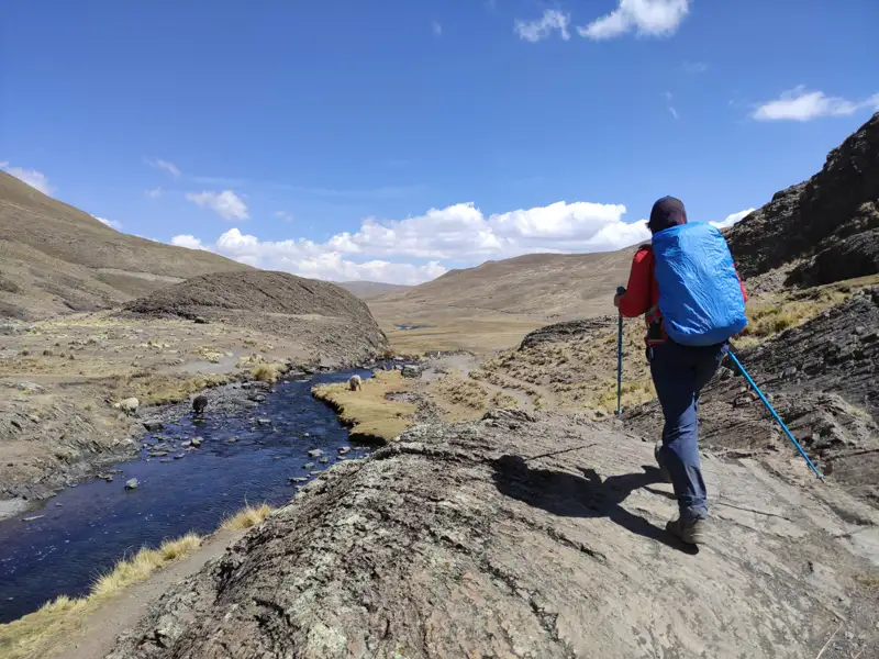 Wanderer auf einem Bergpfad neben einem Fluss.