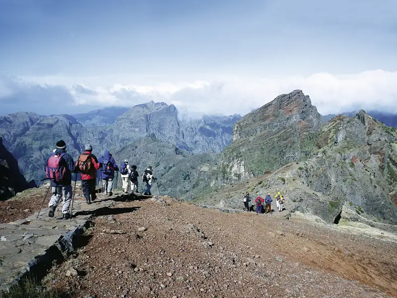 Wanderer auf einem Bergpfad inmitten einer Berglandschaft.